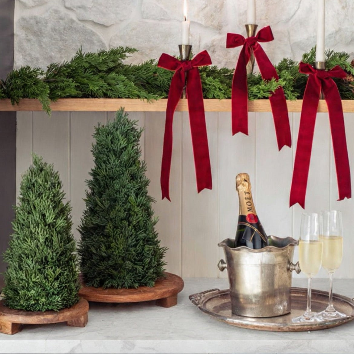 Decorative setup with candles, red ribbons, and a bottle of champagne on a kitchen counter.