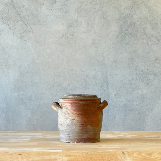 Ceramic pot on a wooden surface with a gray wall background
