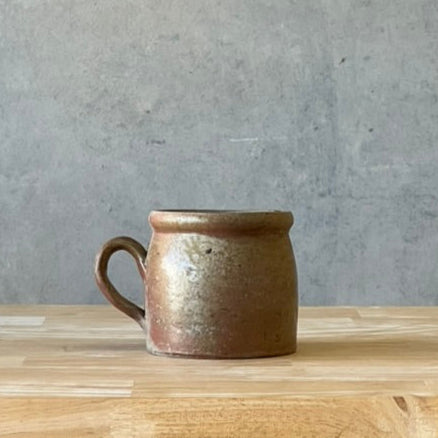 Ceramic mug on a wooden surface with a concrete wall background