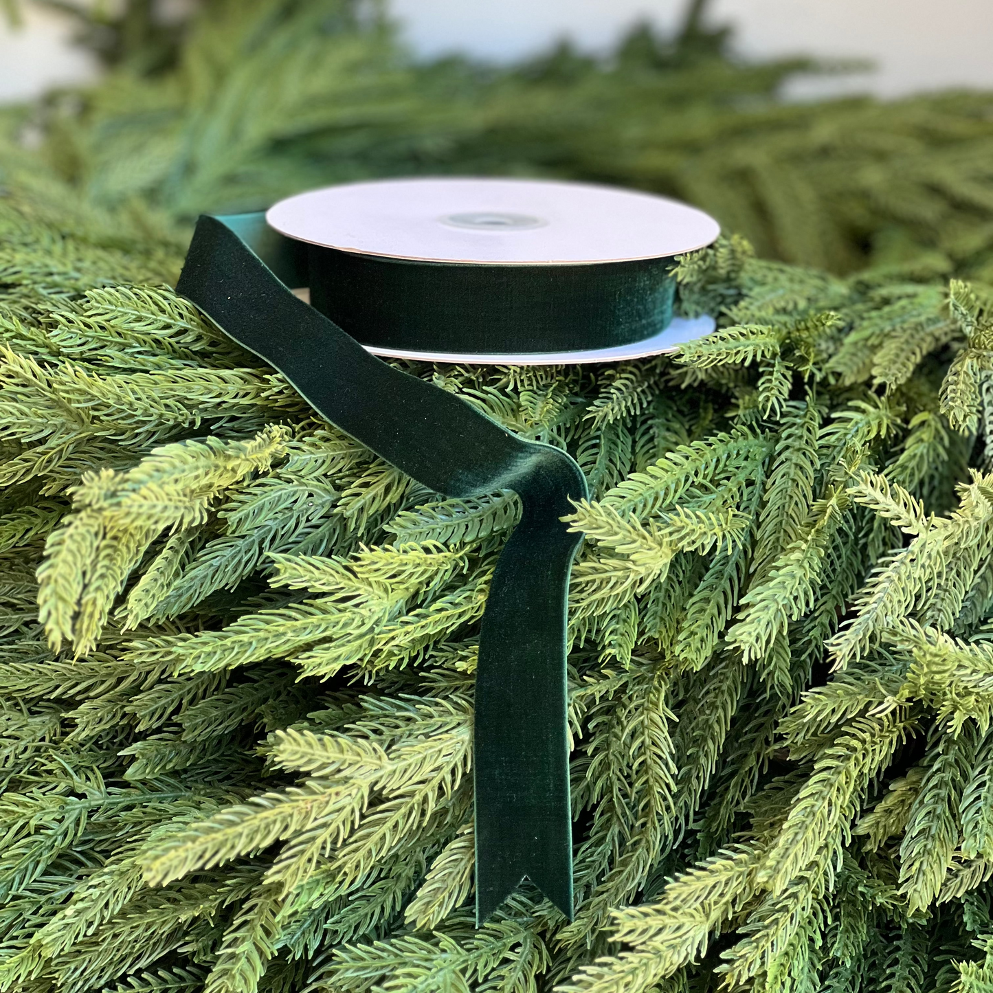 Green ribbon on a spool with a Christmas tree in the background