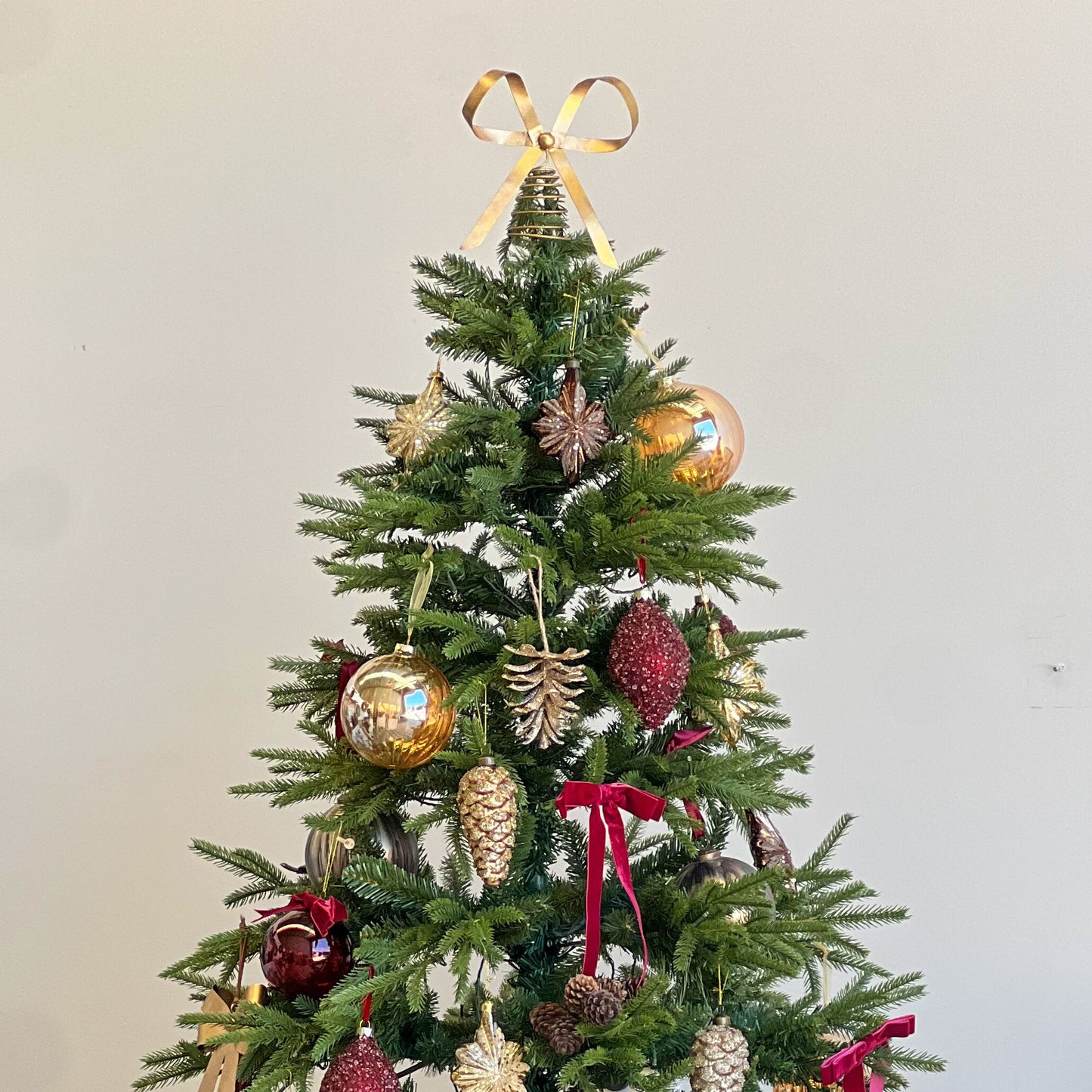 Decorated Christmas tree with ornaments and ribbons in a room setting.