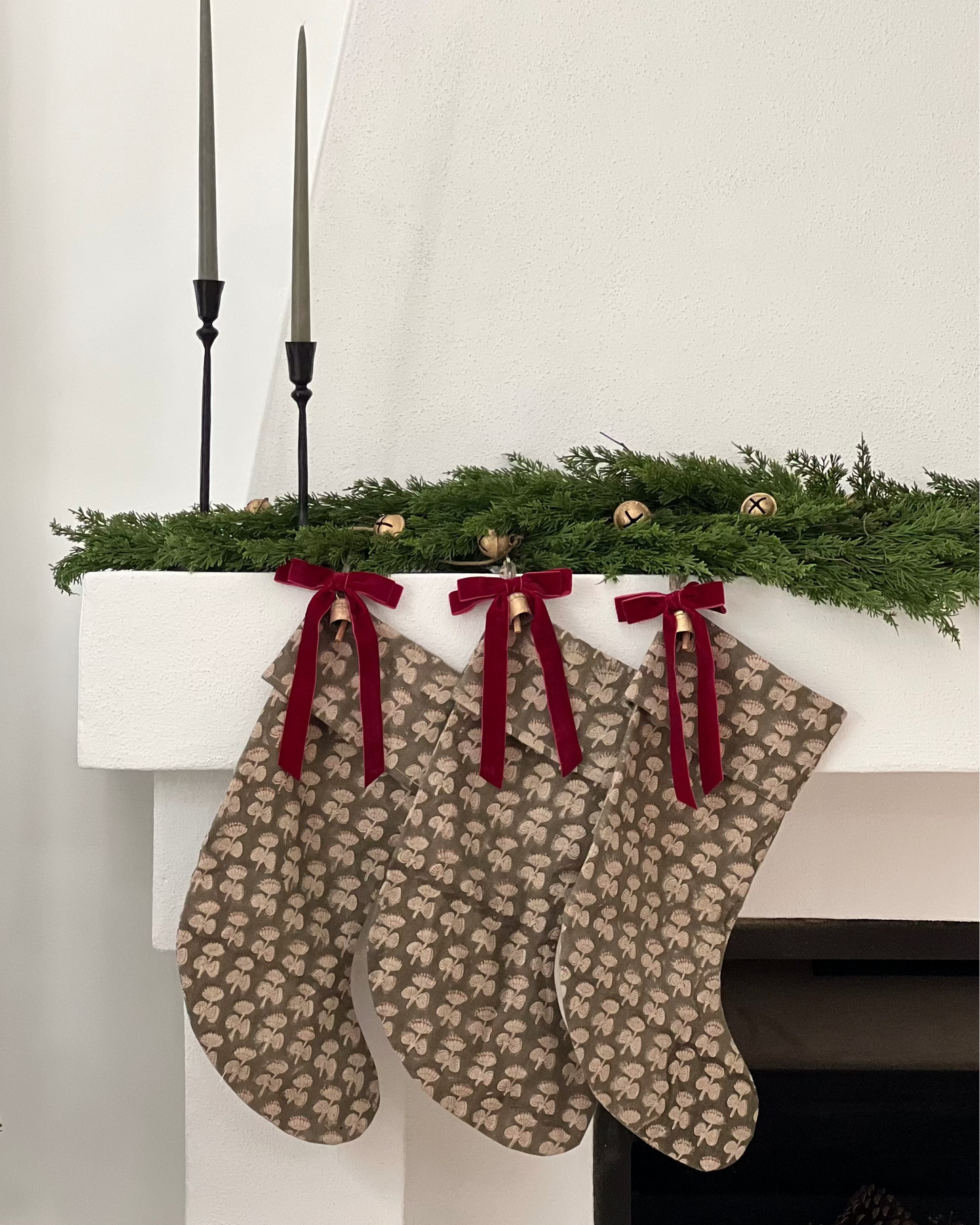 Two patterned stockings hanging on a fireplace mantel with Christmas decorations.