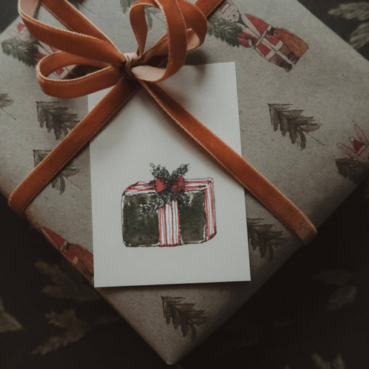 Hand-painted Christmas wrapping paper and gift tags with a wrapped present. 