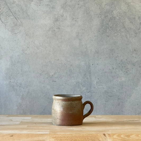 French confit pot on a wooden surface with a concrete wall background