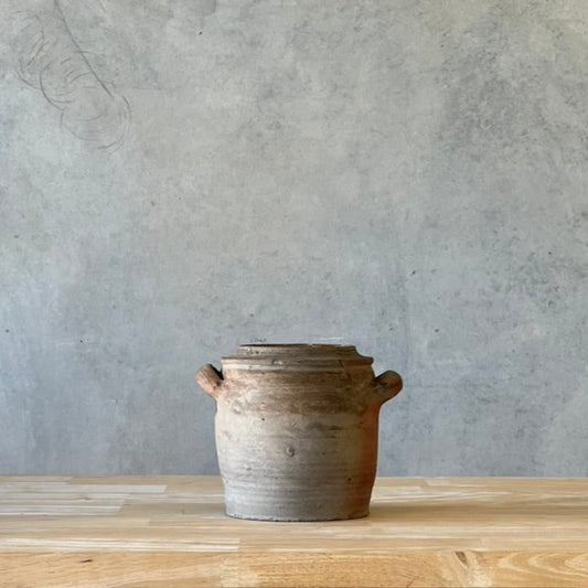 Ceramic pot on a wooden surface with a gray wall background