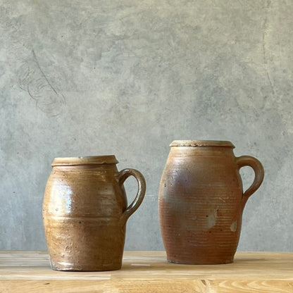 Two ceramic jars on a wooden surface with a gray wall background