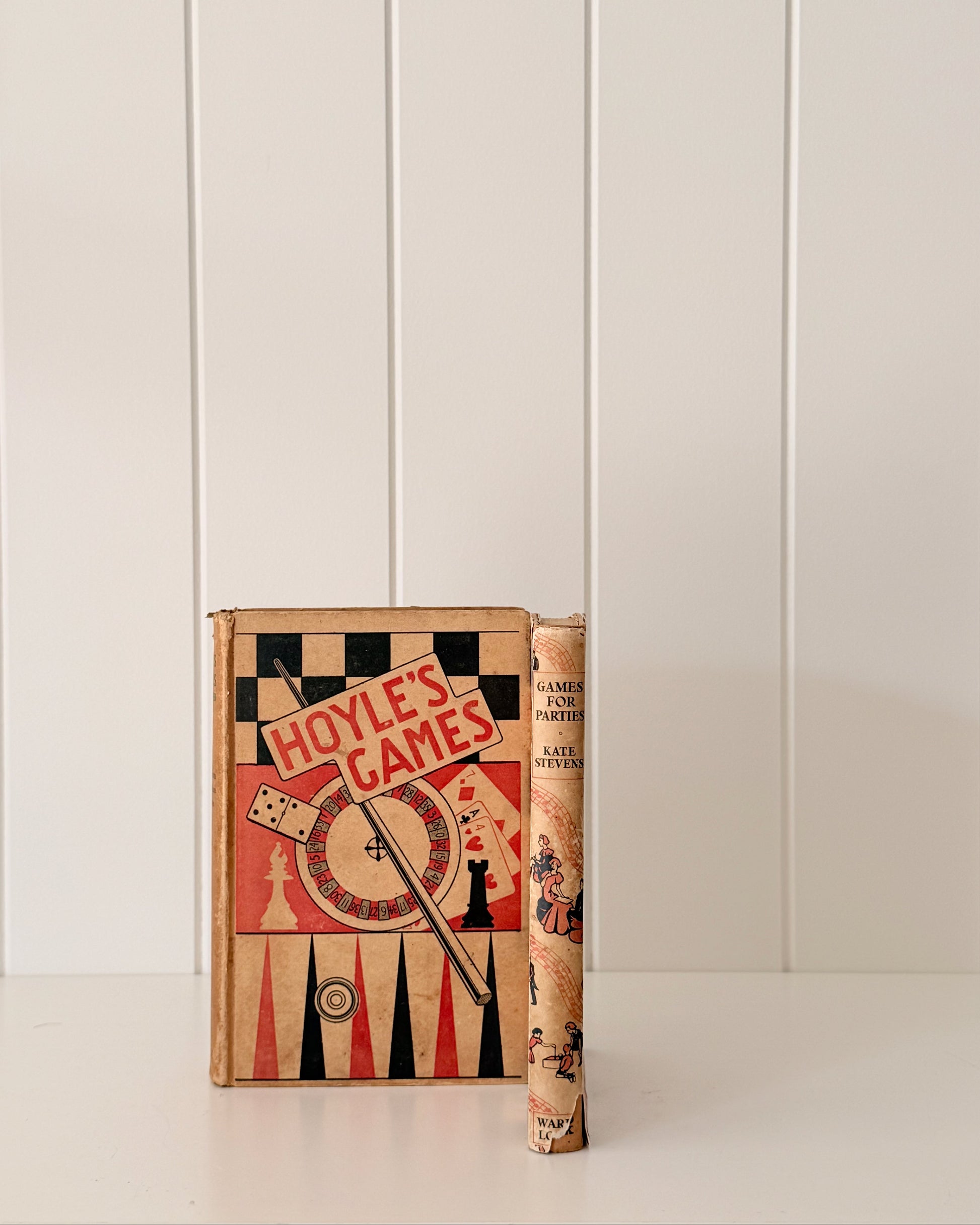 Vintage book titled 'Hoyle's Games' on a white surface with a white paneled wall background