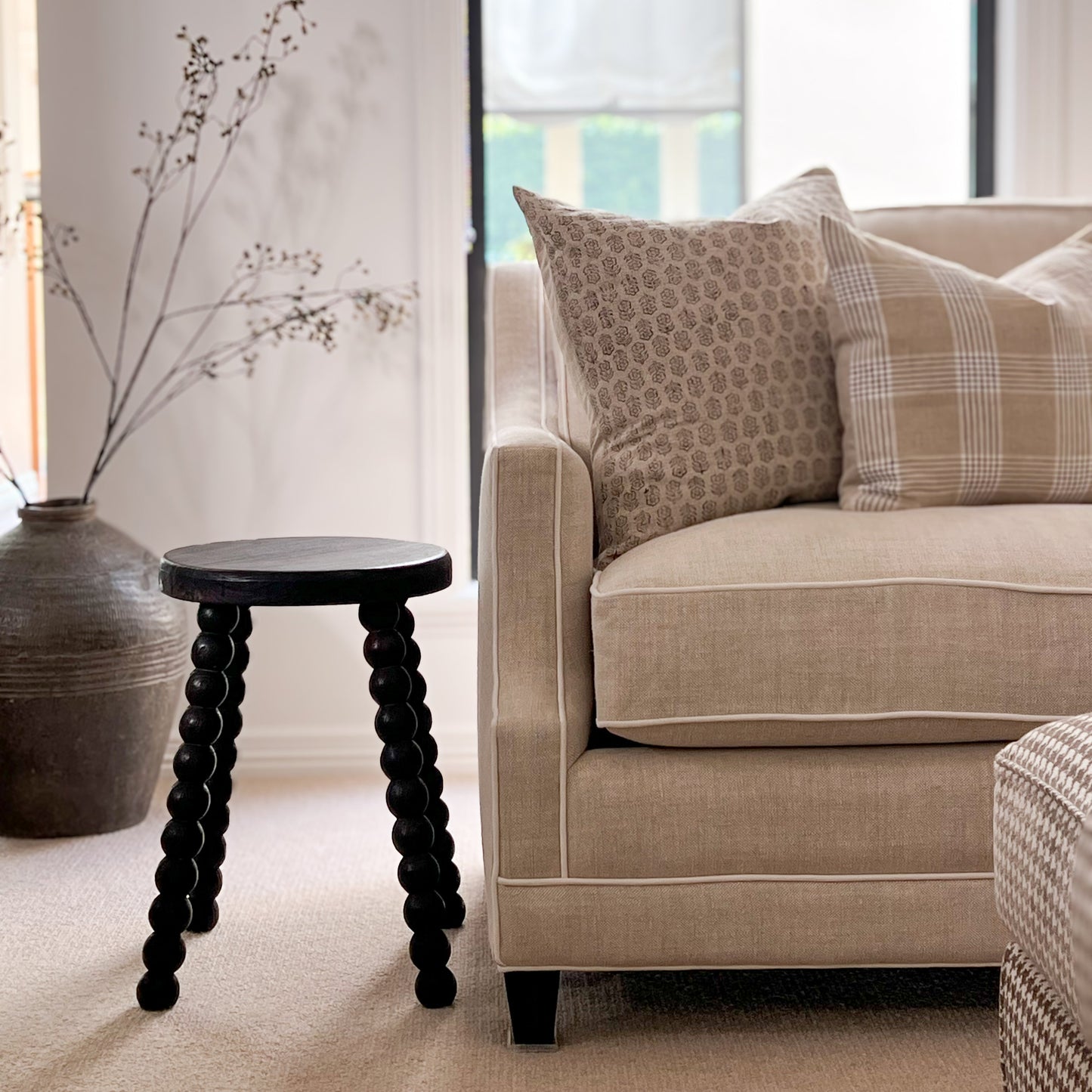 timber Bobbin Stool next to sofa with block print cushion.