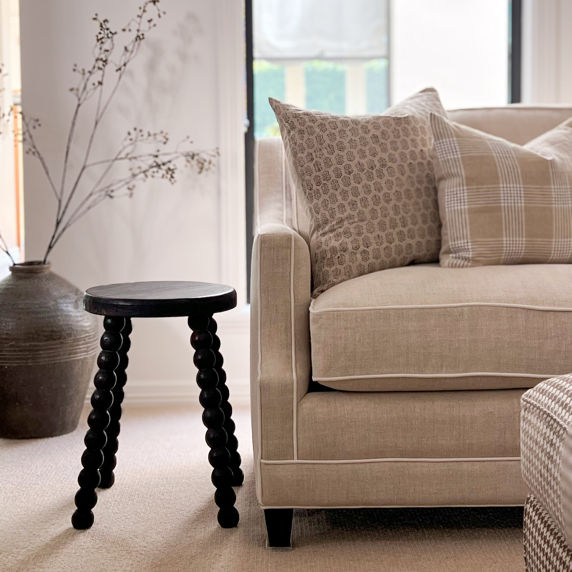 timber Bobbin Stool next to sofa with block print cushion.