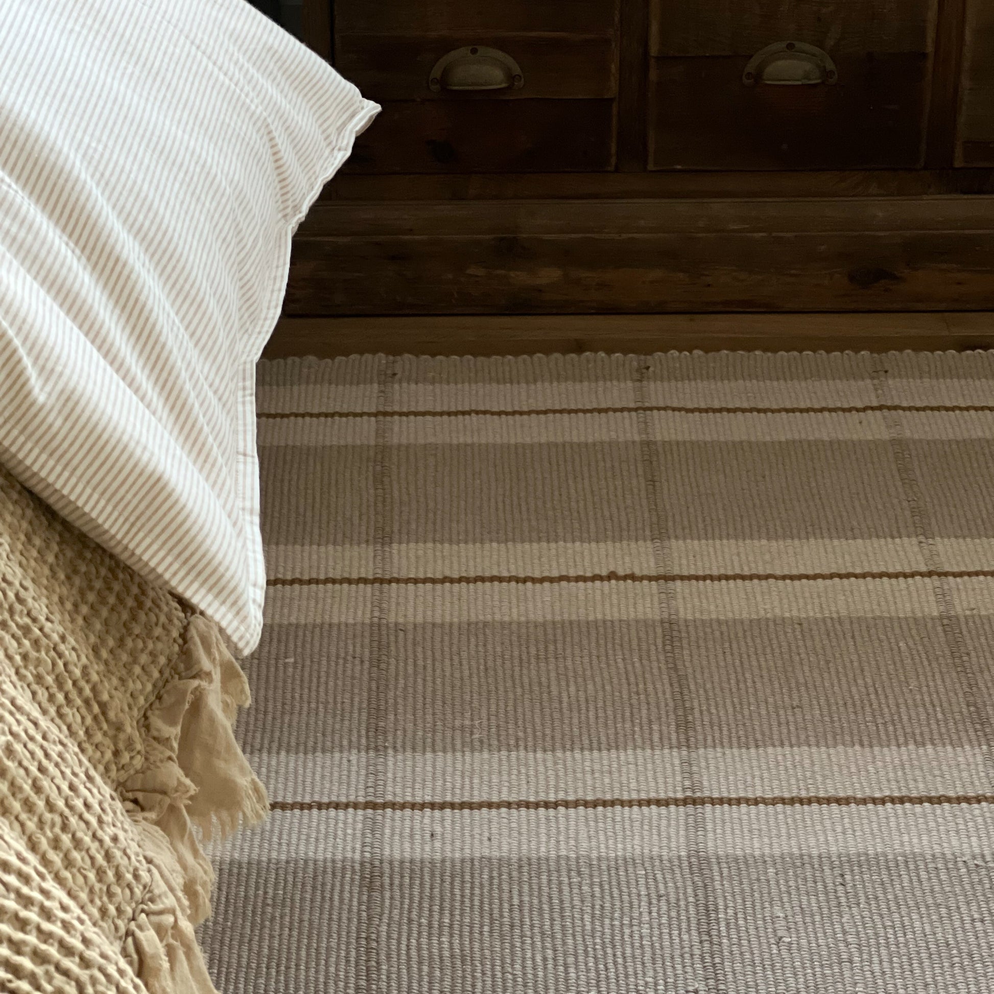 Plaid patterned rug in a room with wooden furniture and a textured blanket.