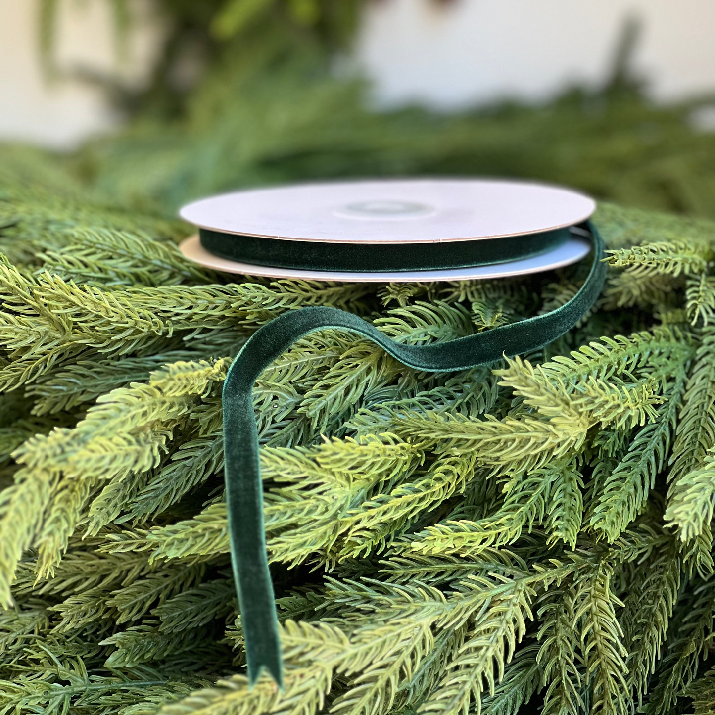 Green ribbon on a roll with a Christmas tree background