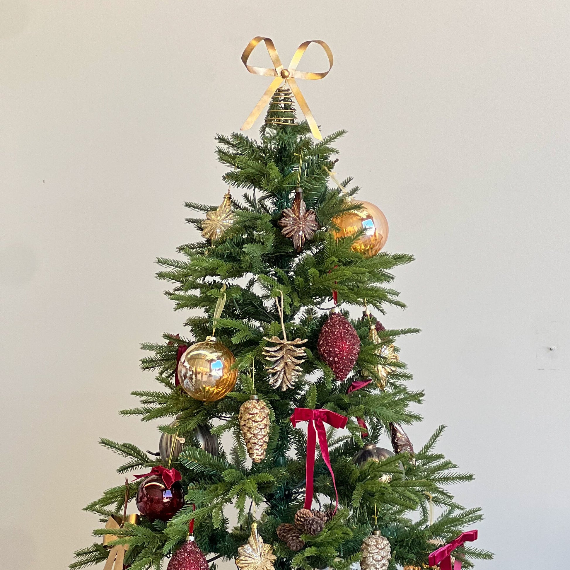Decorated Christmas tree with ornaments and ribbons in a room setting.