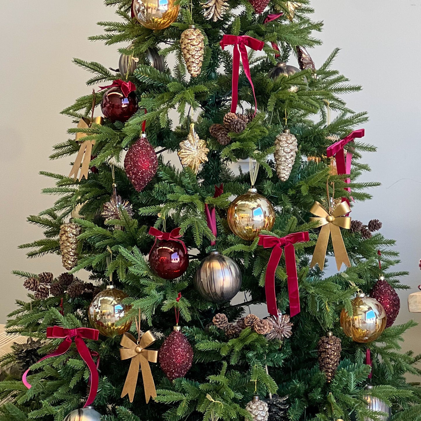 Decorated Christmas tree with ornaments and ribbons in a room setting.