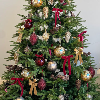 Decorated Christmas tree with ornaments and ribbons in a room setting.