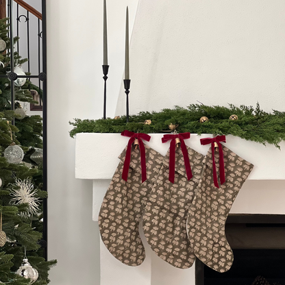 Two patterned stockings hanging on a fireplace mantel with Christmas decorations.